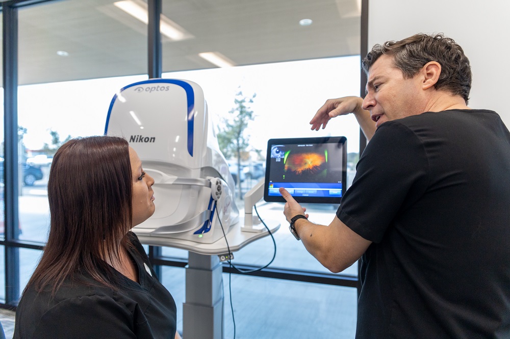 An eye doctor explains detailed retinal imaging results to a patient using a high-resolution Optos Nikon scanner. The consultation highlights the importance of early detection and thorough eye health evaluations – Eye Doctor.