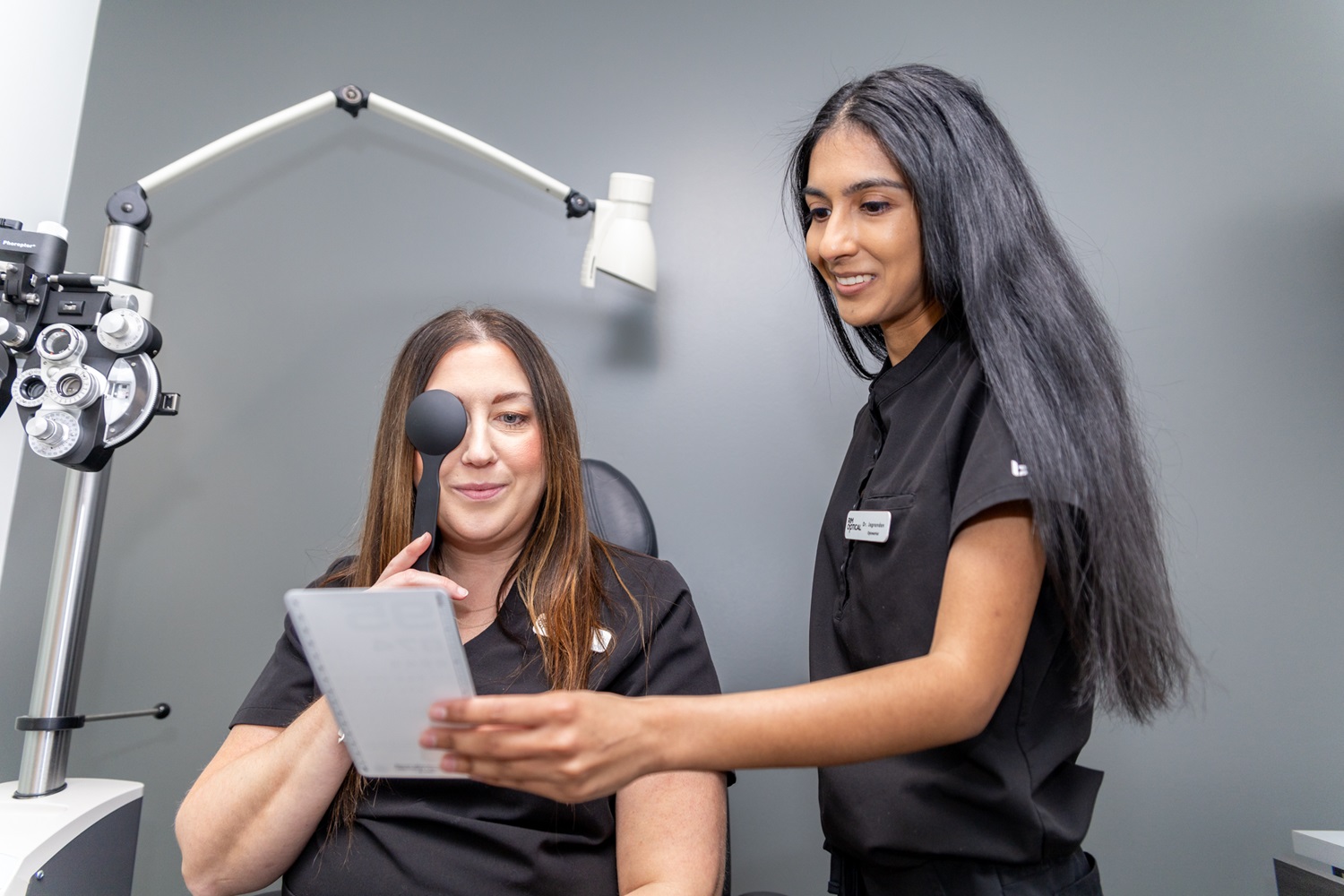 A patient sits at a slit lamp machine while the provider examines the front structures of the eye. This detailed evaluation is vital for diagnosing dryness, irritation, infections, and other eye health concerns – Eye Exams.
