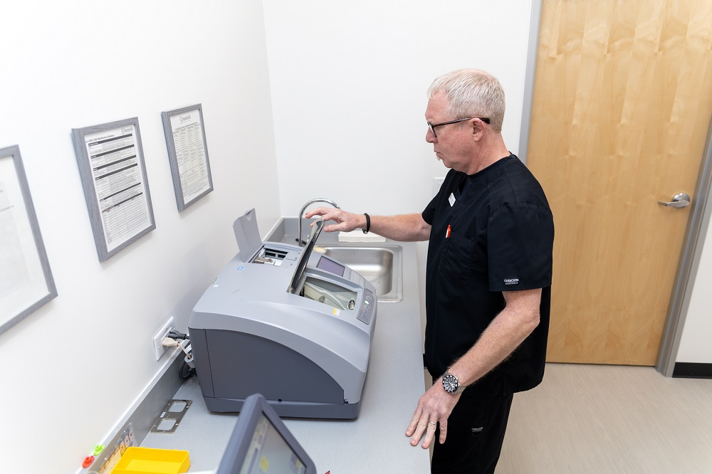 On-Site Lens Crafting and Eyeglass Preparation – Georgetown Eyeglasses A skilled optician operates advanced lens-cutting equipment in the lab, ensuring each pair of eyeglasses is crafted with precision for optimal clarity and comfort. – Georgetown Eyeglasses