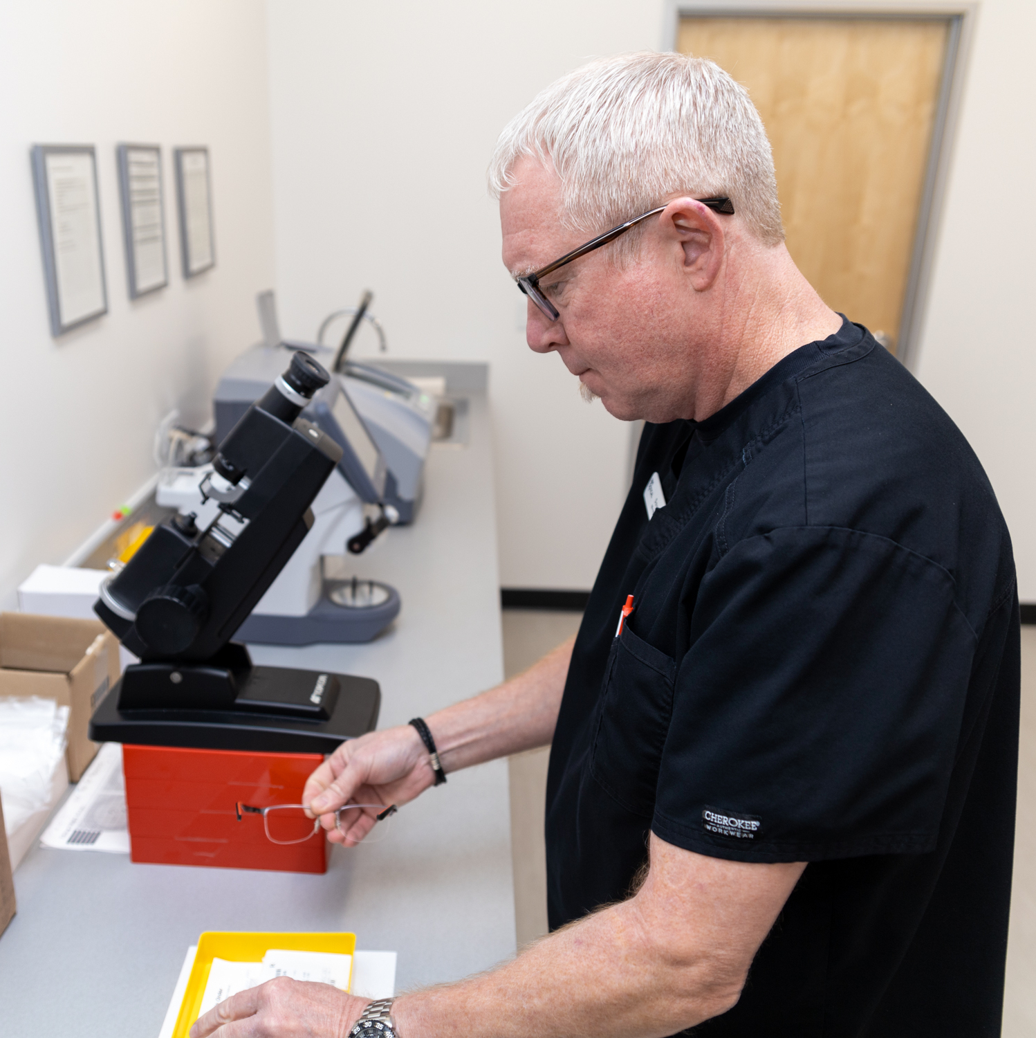 An optician examines a pair of lenses using specialized equipment to ensure accuracy and quality. Proper lens verification is an important part of providing clear and reliable vision correction – Vision Exams.